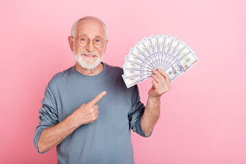 Photo of pretty positive guy pensioner dressed grey pullover glasses pointing money fan isolated...
