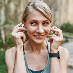 Young smiling sports woman put wireless earphones