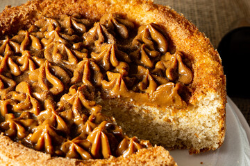 typical brazilian churros cake with dulce de leche, on a table with plates and coffee, comfortable breakfast or snack scene