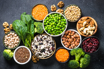 Vegan protein source, healthy nutrition food. Legumes, beans, nuts, vegetables and seeds. Top view on black stone table.