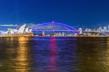 Naklejka premium Colourful Light show at night on Sydney Harbour NSW Australia. The bridge illuminated with lasers and neon coloured lights 