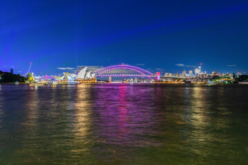 Obraz premium Colourful Light show at night on Sydney Harbour NSW Australia. The bridge illuminated with lasers and neon coloured lights 