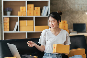 Portrait young attractive asian female owner startup business work happy with box at home prepare parcel delivery in sme supply chain, start up small business concept.