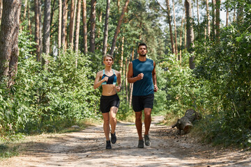 Front of sports couple running on path in forest