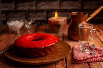 coffee with red pudding for breakfast and snack on a wooden table with the light of a candle and bronze coffee pot and glass sugar bowl