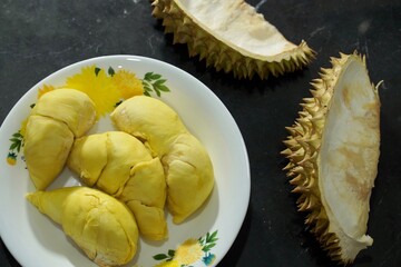Fresh durian in packaging on white dish with durian peel on banner black  background. Durian king...