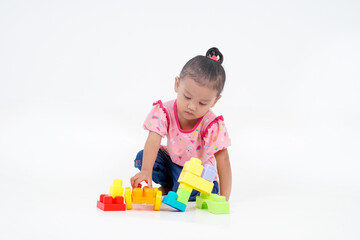 Lovely little cute asian girl playing on the floor with lots of colorful plastic blocks in studio, isolated on white background