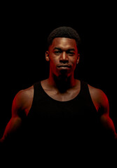 Basketball player with red side light against black background. Serious concentrated african american man..
