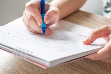 Woman hand with pen writing on calendar date business planning appointment meeting concept