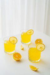 refreshing citrus drink and lemon slices on white tabletop and blurred background.