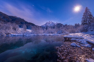 Zelenci springs lake in winter with the mountains reflection after fresh snow. 