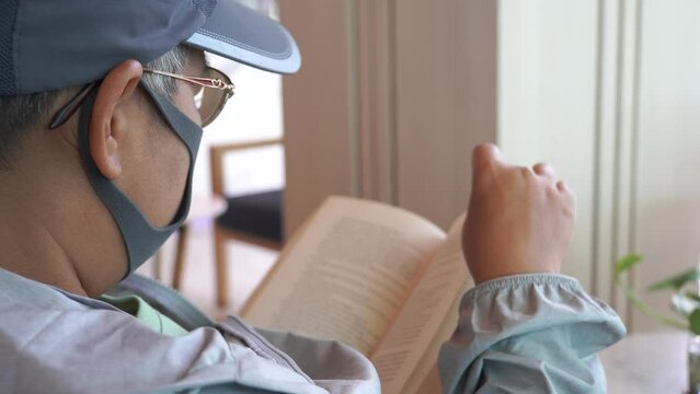 person relaxing. Smart Asian travers with facemask opening pages of book, Reading textbook for education learning, People cognitive knowledge and study searching information at home or hotel.