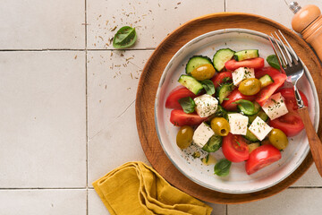 Greek salad. Fresh Greek salad with fresh vegetables, tomato, cucumber, green olives and feta cheese on old grey concrete table background. Top view.