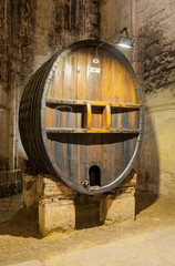 Ancient wine barrel used for aging wine on display in a cellar