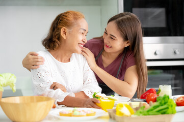 Obraz na płótnie Canvas mother and daughter cooking in the kitchen, mother and daughter hugging to love on mother's day, Asian family