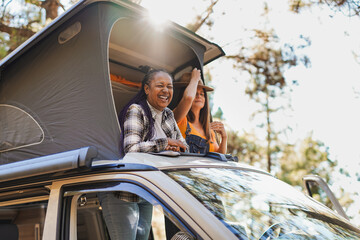 Happy mature female friends enjoy day at mountain forest during camping vacation with mini van