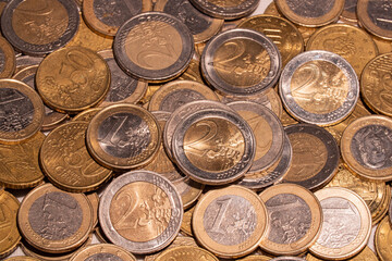 Heap of different euro coins. A lot of one euro, two euro and fifty cent coins on a table. European currency. 