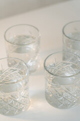 close up view of faceted glasses with fresh water on grey background.