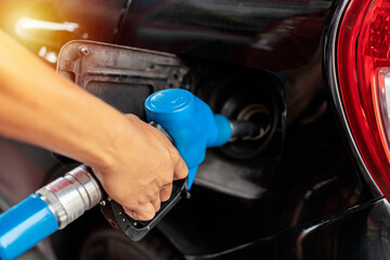 Refueling the car at a gas station fuel pump. Man driver hand refilling and pumping gasoline oil
