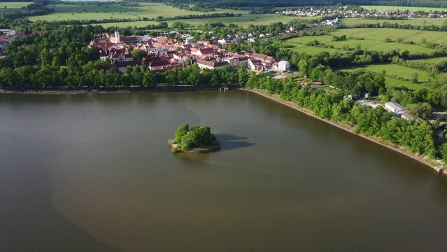 Aerial view of a small historic town Trebon surrounded by a big pond Svet with little island and strong dam with strong old oaks. South Bohemia. Czechia. Central Europe.