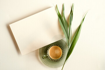 blank white invitation template, rectangle, art canvas texture, soft shadows, leaf decoration, coffee in a green cup, white background, canvas texture, photo taken from above