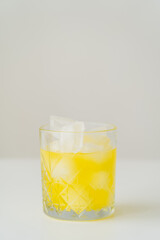 glass with fresh citrus tonic and ice cubes on grey background with copy space.