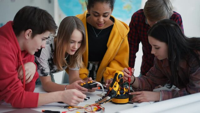 Group of students building and programming electric toys and robots at robotics classroom