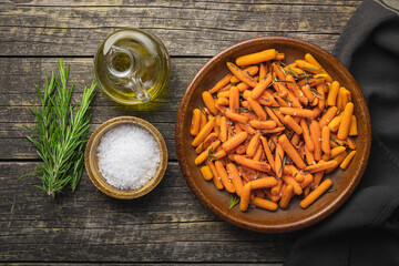 Roasted baby carrots with salt and rosemary on plate.