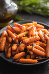 Roasted baby carrots with salt and rosemary on plate.