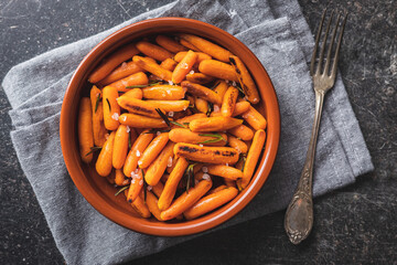 Roasted baby carrots with salt and rosemary in bowl.
