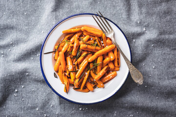 Roasted baby carrots with salt and rosemary on plate.