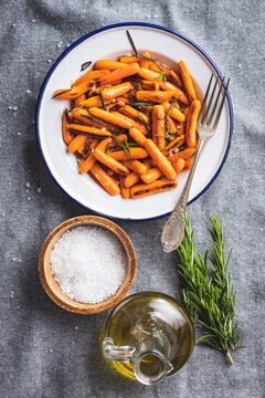 Roasted baby carrots with salt and rosemary on plate.