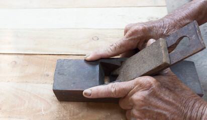 Elderly hands working wood. Chisel on wooden plank carpentry.