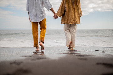 Young loving couple shown from behind holding hands on a beach