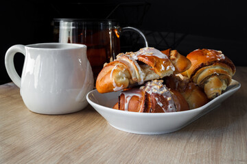 St. Martin's croissants. Fresh traditional polish pastry with poppy-seed filling and nuts. Rogal marciński or świętomarciński, with white ceramic tea cup or mug and glass teapot. - obrazy, fototapety, plakaty