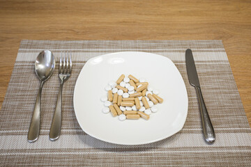 A plate of pills of medicine vitamins instead of lunch with cutlery. Drug intake. Tacking medications. Reception a lot of medicines. Healthy food