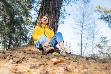 Portrait of a happy smiling young girl sitting in the woods under a tree. Mental health. The woman...