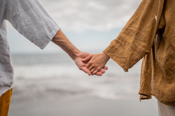 Young couple holding hands on a beach, no faces