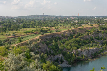 rocks of a flooded granite quarry on a background of cloudy sky