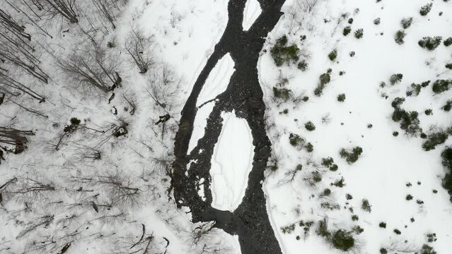 Aerial zoom on a river during winter in the french alps