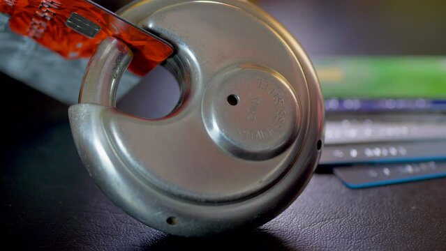 A credit card in the clasp of a closed lock, with other cards nearby. No visible branding or logos. Multi concept shot, whereby the lock represents buyer security, OR borrower debt, OR a fraud / scam.