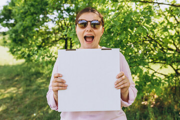 Happy Woman in sunglasses holding a box with pizza on nature background. Fast pizza delivery. Mock...