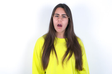 Fototapeta premium Young beautiful brunette woman wearing yellow hoodie over white wall yawns with opened mouth stands. Daily morning routine