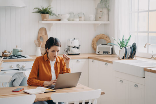 Female Sales Manager Is Working From Home. Lady Freelancer With Laptop Is Taking Notes.