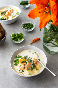 Norwegian salmon red fish soup with vegetables, herbs and cream, top view on the dining table