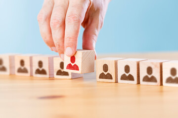 Person icon on wooden cube with hand picked different from the crowd