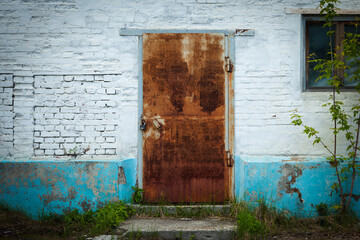 White brick wall with rusty metal door with padlock