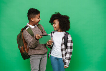 Two african american kids smiling and using tablet computer