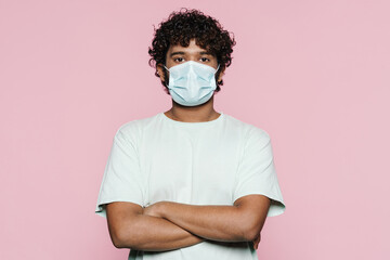 Young curly man wearing face mask posing and looking at camera