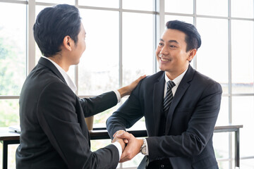 Two Asian business man shaking hands together after discussion business strategy plan in the...
